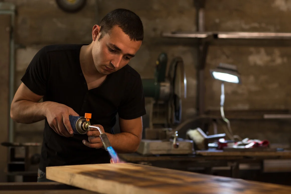 Person bearbeitet Holz mit Gasbrenner